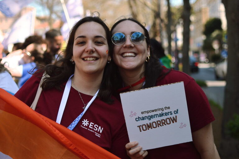 image of two girls holfing a sign that says: empowering the changemakers of tomorrow" during a flag parade