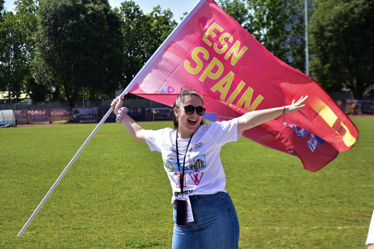 immagine di ragazza che sventola una bandiera con su scritto "ESN Spain" durante le competizioni degli International Erasmus Games